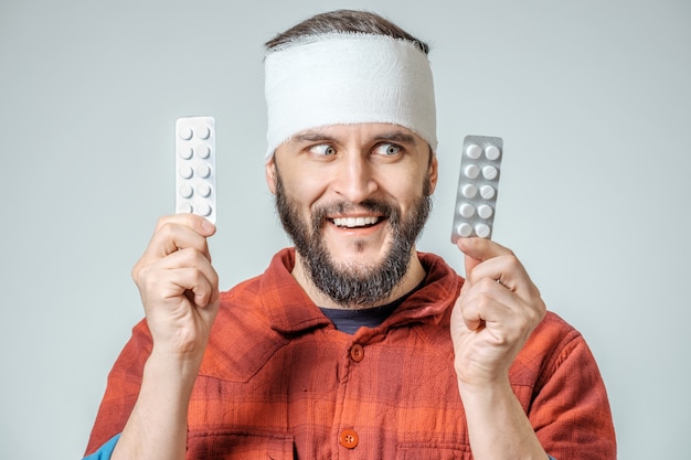 Hombre en vendaje médico con pastillas en una mano