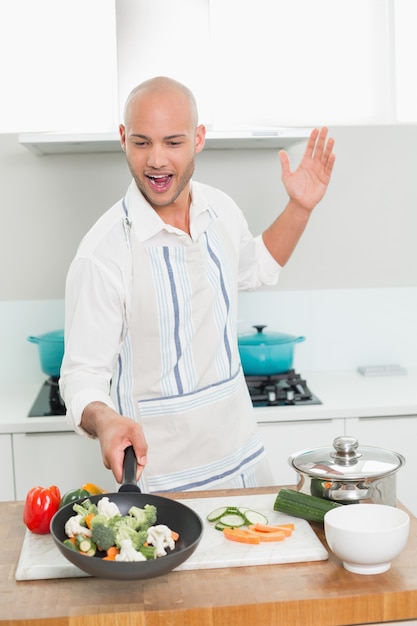 Hombre con verduras en sartén en la cocina