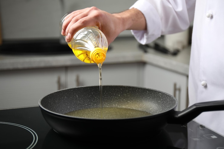 Foto hombre vertiendo aceite de cocina de una botella en la sartén de cerca