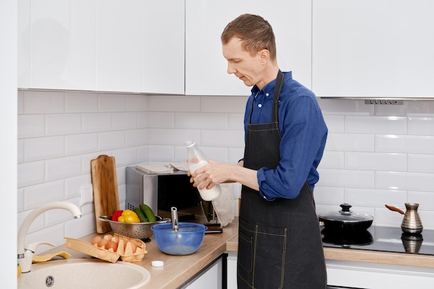 Hombre vertiendo leche en un bol con huevos batidos para hacer una tortilla