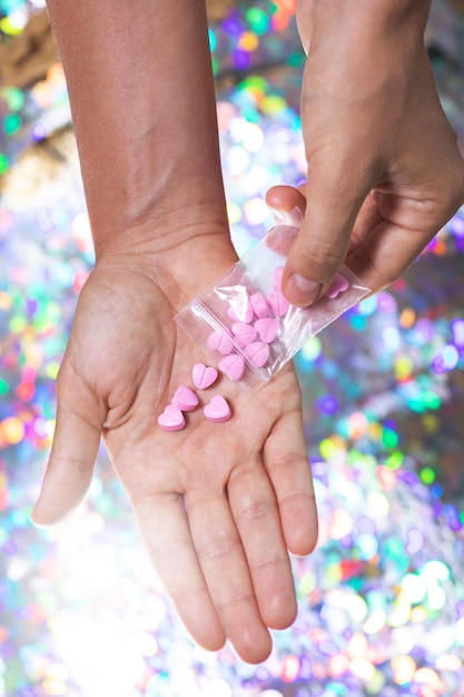 Hombre vertiendo pastillas en forma de corazón en la palma de una bolsa ziplock