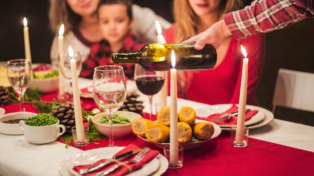 Foto hombre vertiendo winne en la cena de navidad