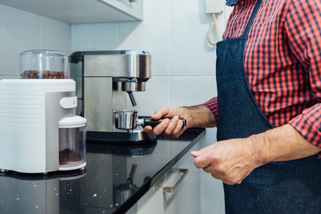 Hombre vestido con camisa a cuadros y delantal preparando un espresso