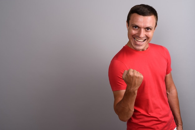 Foto hombre vestido con camisa roja contra la pared gris