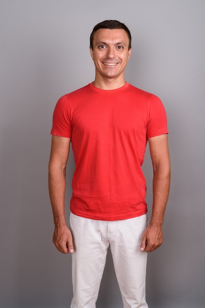 Hombre vestido con camisa roja contra la pared gris