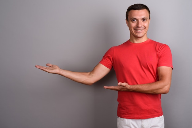 Foto hombre vestido con camisa roja contra la pared gris