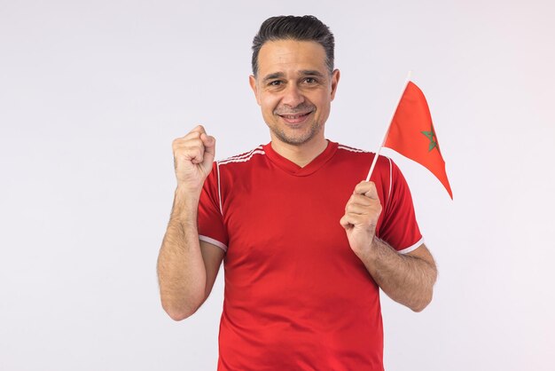 Hombre vestido con una camisa roja sosteniendo una bandera marroquí Copa del mundo deportivo y concepto de ventilador