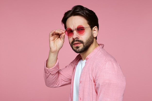 Hombre vestido con camisa rosa y gafas de sol contra rosa