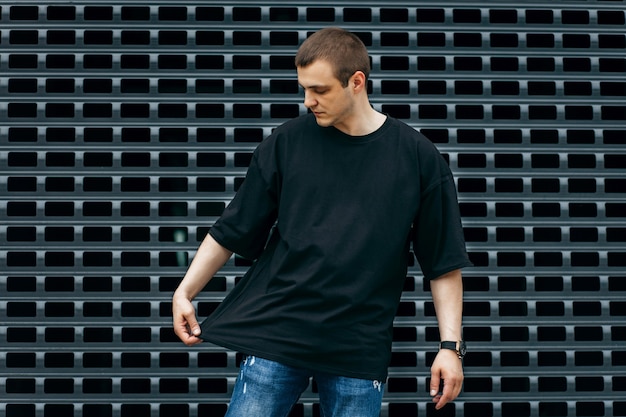 Hombre vestido con camiseta negra en blanco con espacio para su logotipo o maqueta de diseño