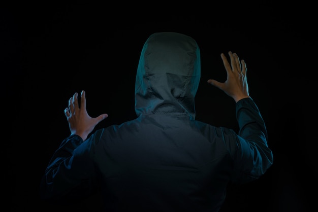 Hombre vestido con capucha en una habitación oscura