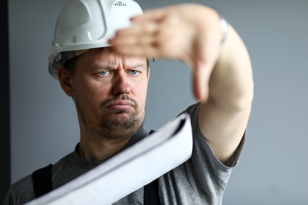 Hombre vestido con casco en manos de control de planos de construcción