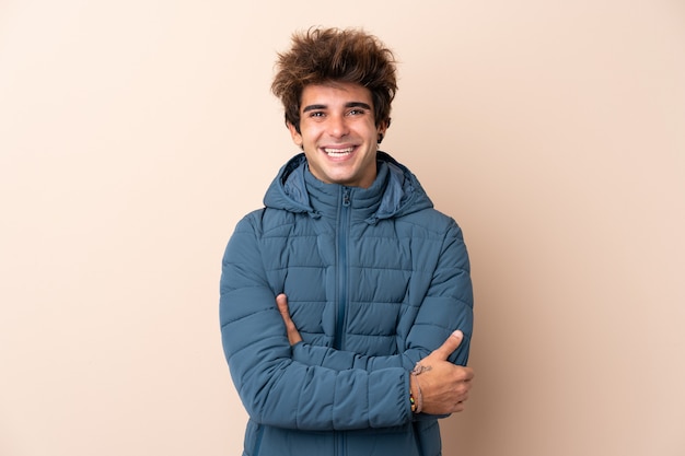 Hombre vestido con chaqueta de invierno sobre pared aislada sonriendo mucho