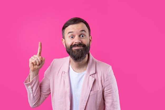 Un hombre vestido con una chaqueta rosa indica la dirección en un fondo rosa aislado