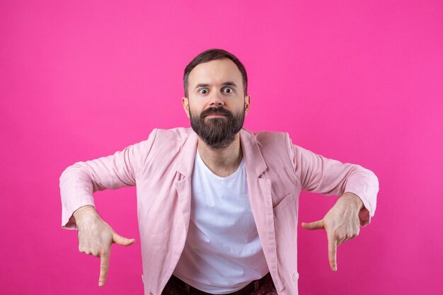 Un hombre vestido con una chaqueta rosa indica la dirección en un fondo rosa aislado