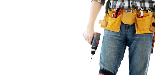 Hombre vestido con cinturón de montaje con herramientas para reparar sosteniendo el taladro en las manos aisladas sobre fondo blanco