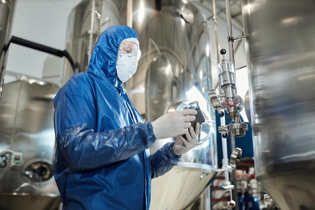 Hombre vestido con equipo de protección que trabaja en el taller de la fábrica de productos químicos industriales