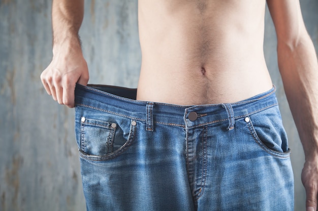 Hombre vestido con jeans de gran tamaño. Pérdida de peso