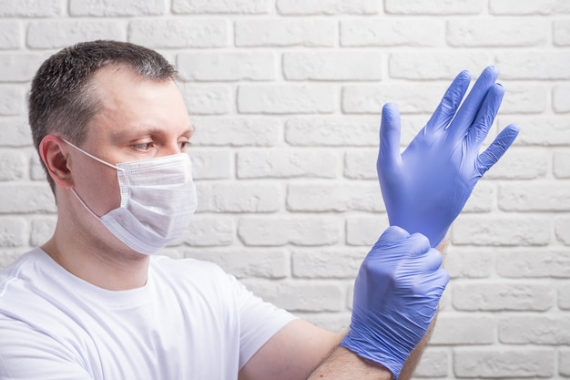 Foto hombre vestido con una máscara médica y guantes protectores contra la pared