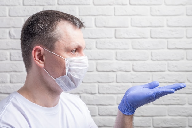 Hombre vestido con una máscara médica y guantes protectores contra la pared