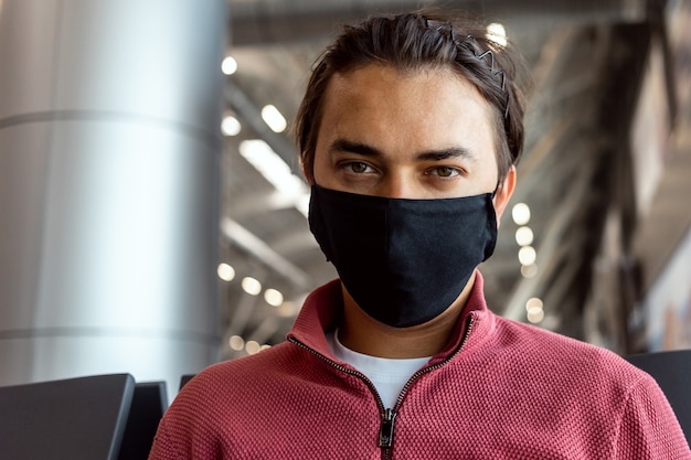 Hombre vestido con mascarilla en el aeropuerto. Los temas viajan en nueva normalidad, coronavirus y protección personal.