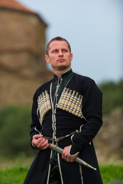 Hombre en vestido nacional georgiano sobre un fondo de montañas