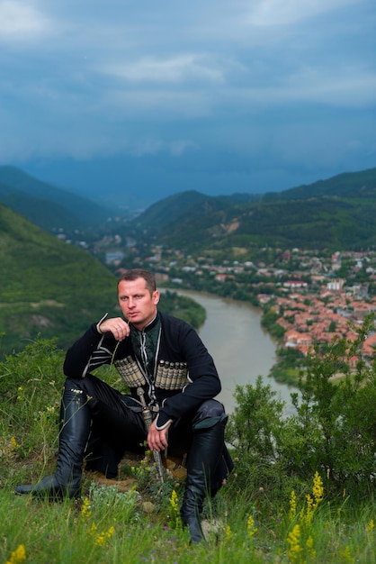 Hombre en vestido nacional georgiano sobre un fondo de montañas