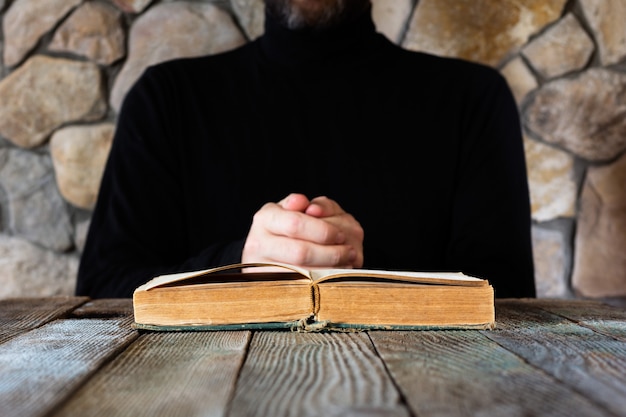 Un hombre vestido de negro frente a un viejo libro abierto.