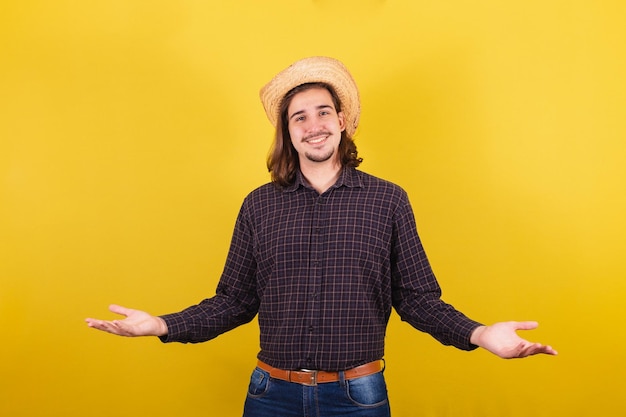 Hombre vestido con ropa típica de fiesta Junina Con los brazos abiertos bienvenidos recibiendo invitando