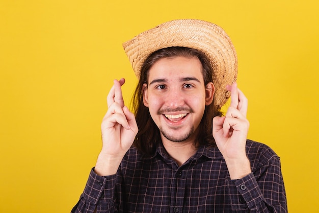 Hombre vestido con ropa típica de fiesta Junina Dedos cruzados deseando esperando querer tanto Símbolo de la suerte