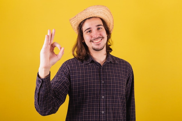 Hombre vestido con ropa típica de fiesta Junina haciendo bien firmar con los dedos