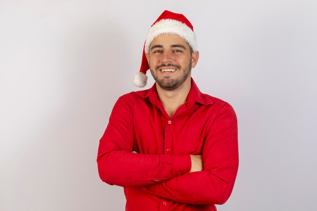 Hombre vestido con sombrero de navidad sobre fondo blanco aislado con los brazos cruzados y mirando hacia adelante