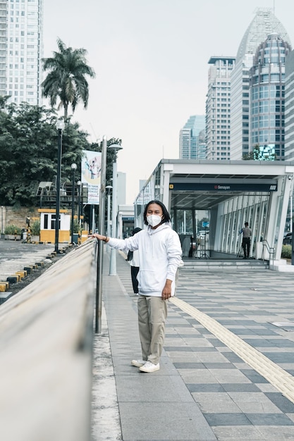 Foto hombre vestido con una sudadera con capucha posando en la calle de la ciudad.