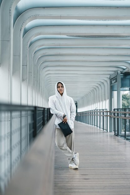 Foto hombre vestido con sudadera con capucha posando en el puente peatonal