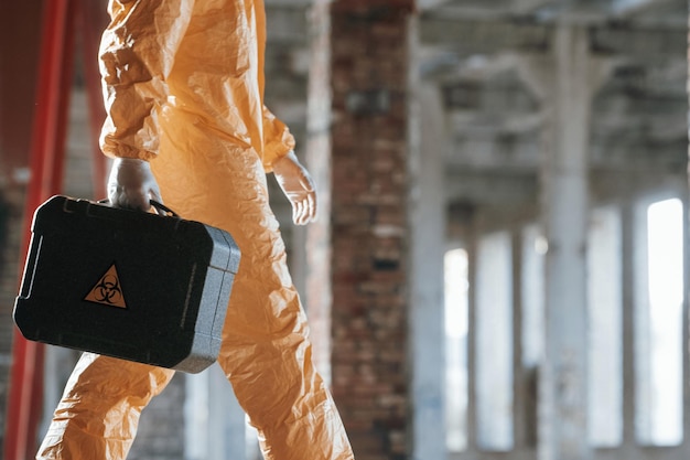 Foto hombre vestido con traje de protección química en las ruinas del edificio postapocalíptico