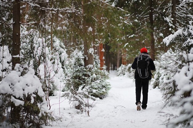 Un hombre viaja con mochila. Caminata de invierno en el bosque. Turista en un paseo en invierno en el parque.