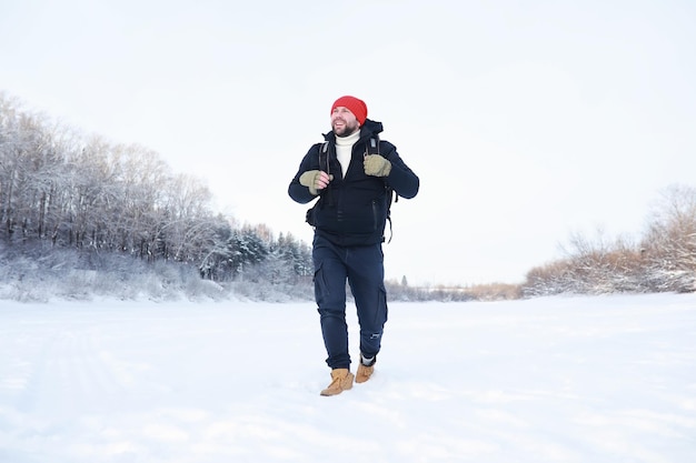 Un hombre viaja con una mochila caminata de invierno en el bosque turístico en un paseo en el invierno en el parque