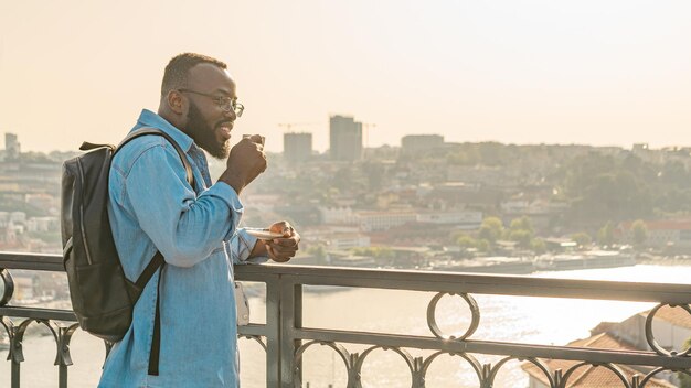 Hombre viajero bebiendo café en el puente de Oporto