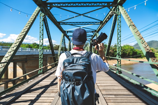 Hombre viajero con cámara en un puente oxidado