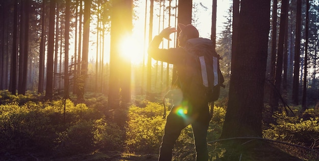 Hombre viajero caminando por el bosque y mirando a la luz del atardecer - Imagen del concepto de vida de viaje