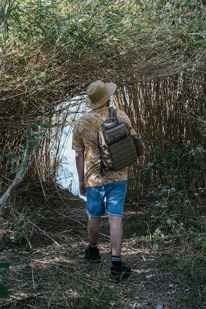 Foto hombre viajero caminando por un sendero lleno de vegetación