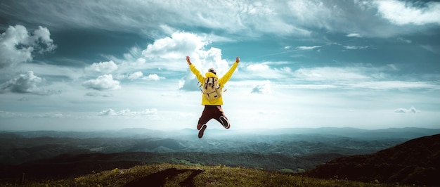 Hombre viajero en la cima de la montaña disfrutando de la vista de la naturaleza con las manos levantadas sobre las nubes