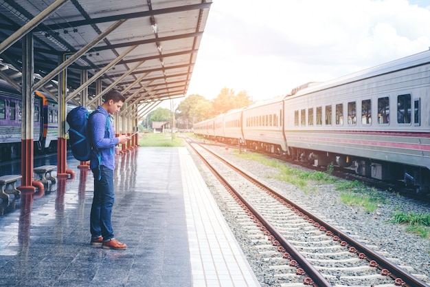 El hombre viajero espera el tren en la plataforma ferroviaria