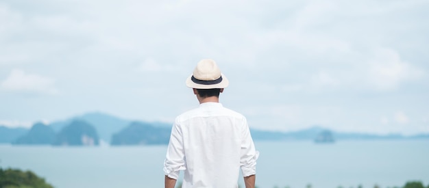 Hombre viajero feliz con camisa blanca disfrutar de la hermosa vista solo Turista con sombrero de pie y relajarse sobre el concepto de verano y vacaciones de viaje por mar