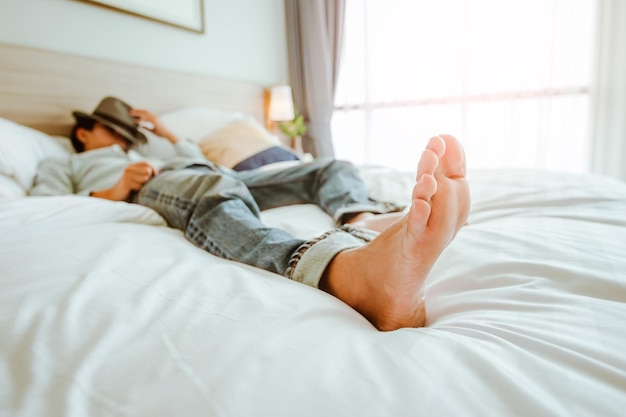 Hombre viajero feliz relajándose en el concepto de vacaciones de viaje de cama blanca