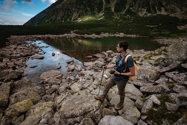 Hombre Viajero con mochila cerca del lago de montaña Concepto de estilo de vida de viaje Concepto de viaje y vida activa con equipo Aventura y viaje en la región montañosa de Polonia Tatri