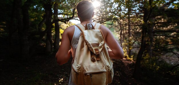 Hombre viajero con mochila de senderismo al aire libre en el bosque al atardecer de verano