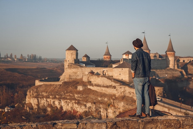 Hombre viajero con una mochila y un sombrero se encuentra en el fondo del antiguo castillo