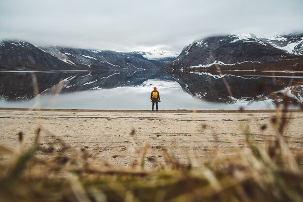 Hombre viajero de pie en el fondo de las montañas y el lago disfrutando del paisaje en Lofoten, Noruega