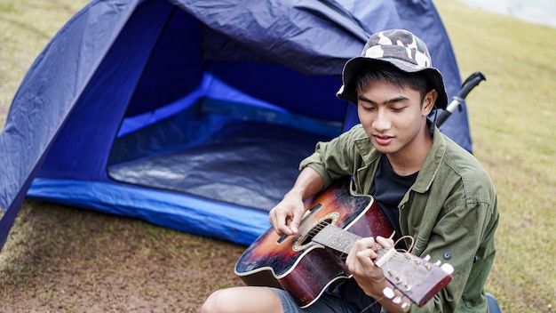 Hombre viajero tocando la guitarra en el campamento