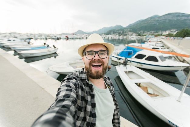 Hombre viajero tomando selfie de yates de lujo marinos durante el viaje de un día soleado y el concepto de verano